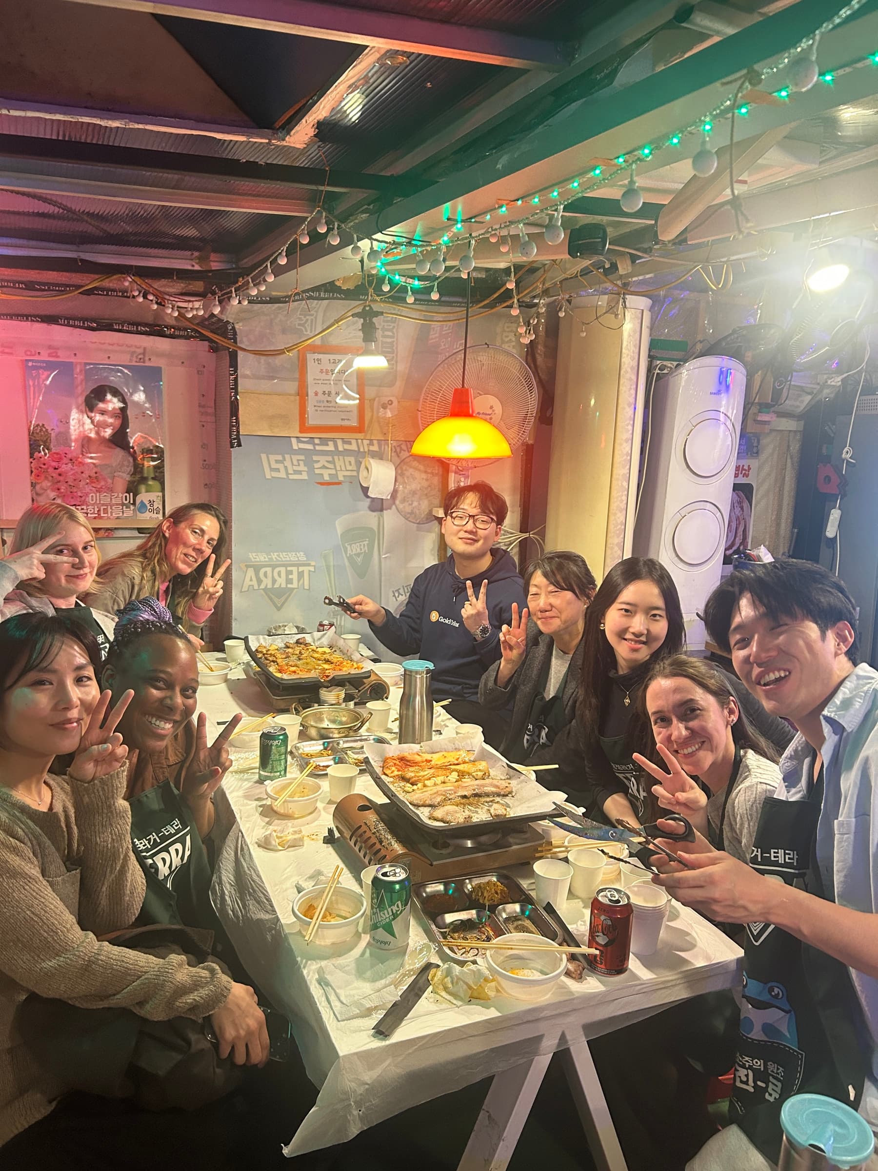 KND neighbors sharing a Korean BBQ dinner and flashing peace signs around the table