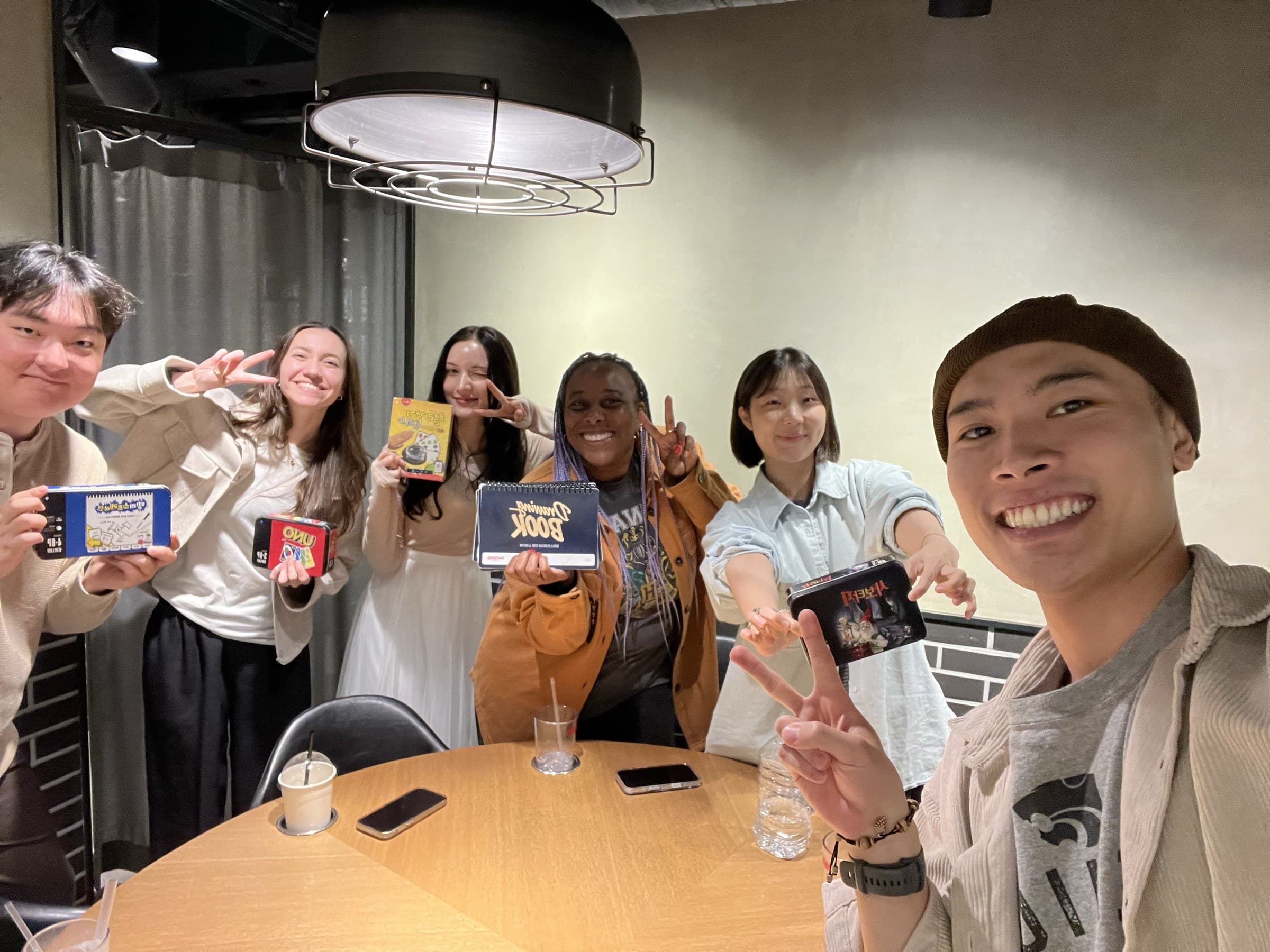 KND friends holding up board games at a board game cafe in Seoul