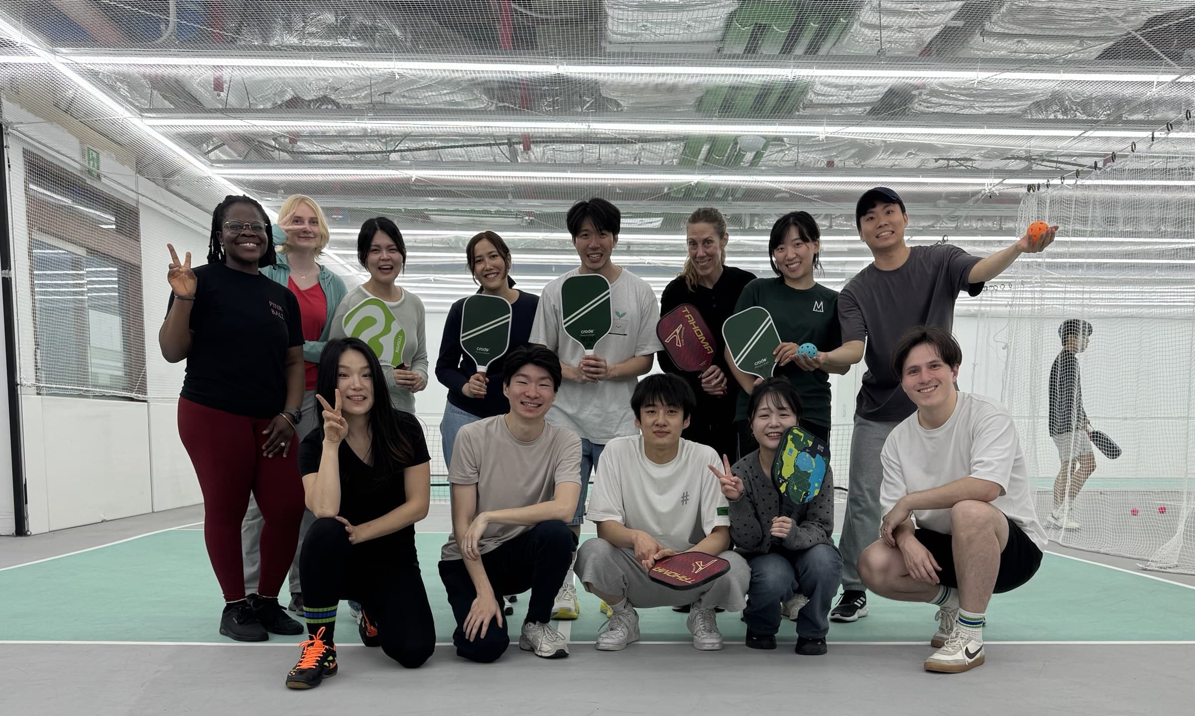 KND neighbors posing with paddles on an indoor pickleball court in Seoul